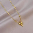 Elegant gold necklace with heart pendant and bead accents displayed on soft fabric.