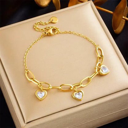 A gold-colored charm bracelet with heart-shaped pendants, presented in a box.