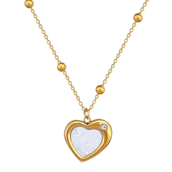 Gold chain necklace with beaded detailing, heart-shaped white enamel pendant, and diamond accent.