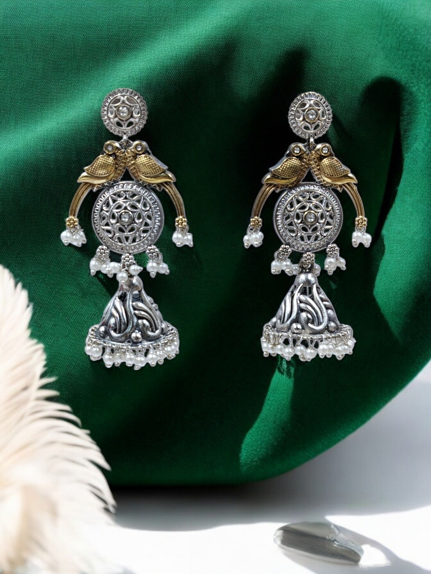 Oxidized silver jhumka earrings with golden bird motifs, circular carvings, pearl drops and antique festive charm.