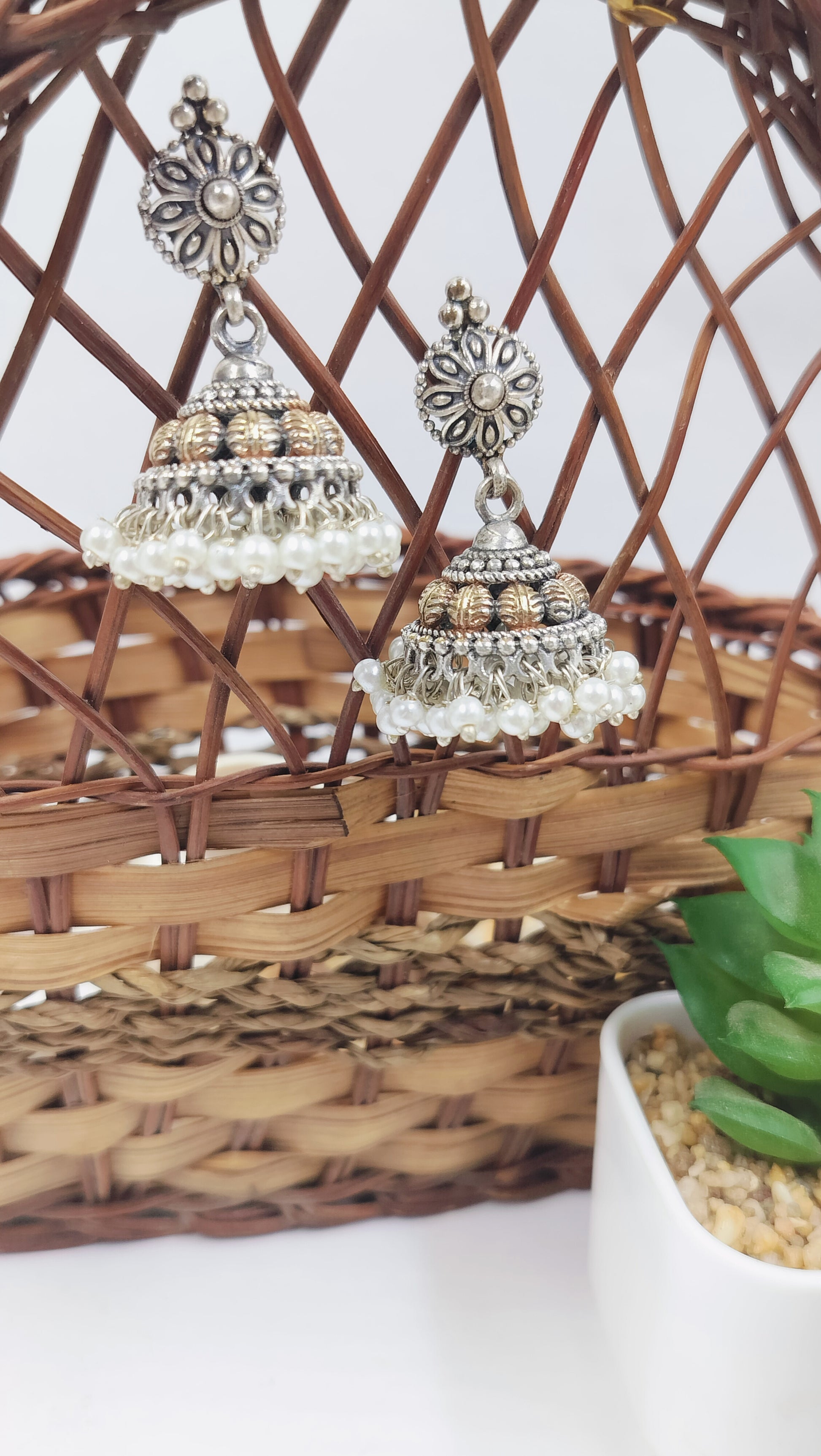 Oxidized silver jhumka earrings with floral stud design, golden highlights, and layered pearl drops – ideal for festive and ethnic wear.