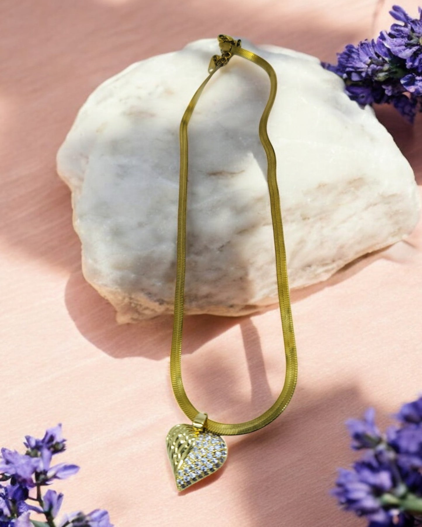 Gold necklace with crystal-studded heart pendant, elegant statement jewelry on wide chain.
