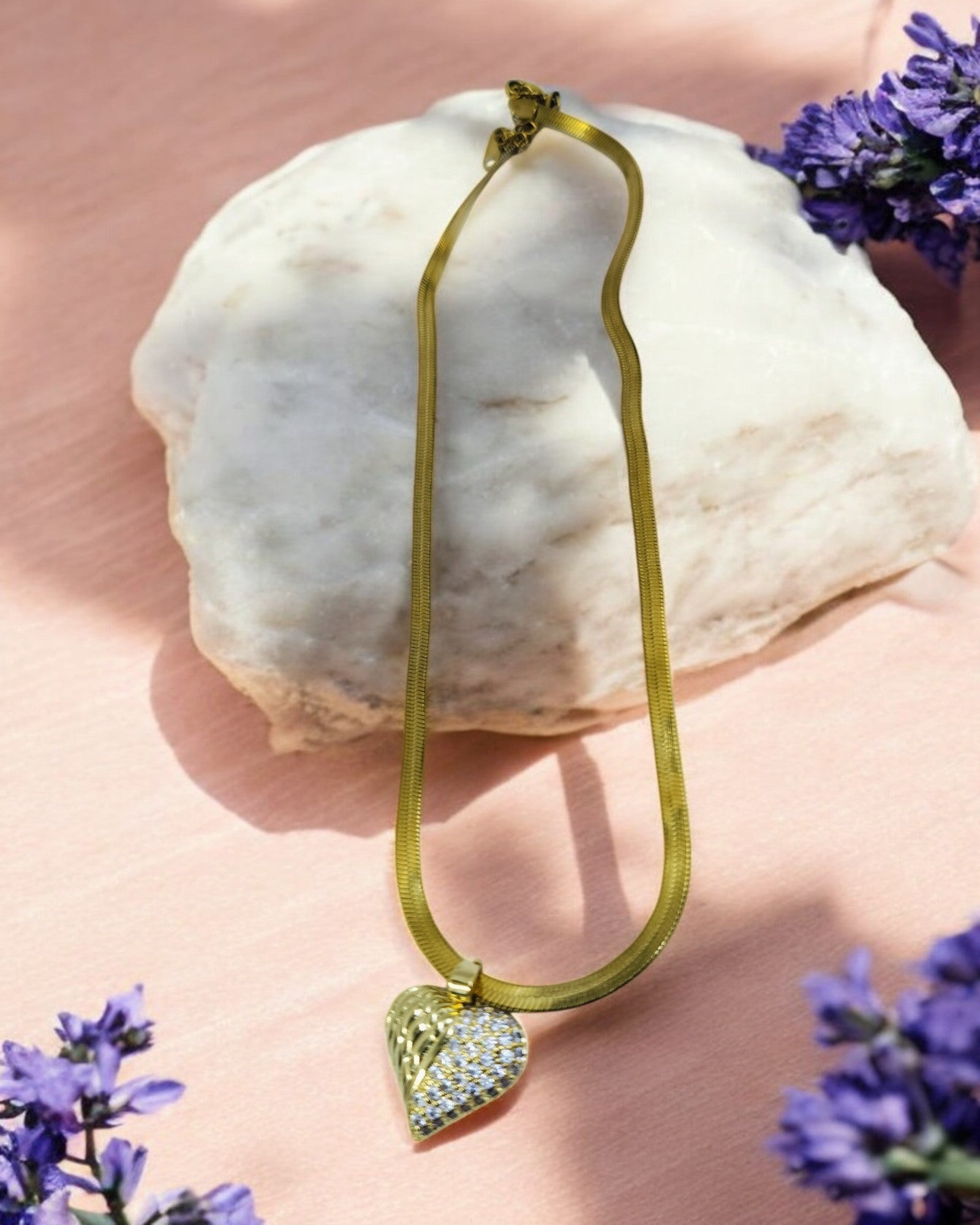 Gold necklace with crystal-studded heart pendant, elegant statement jewelry on wide chain.