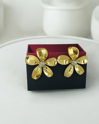 A pair of dual tone large flower stud statement earrings displayed in a black box with a red interior.