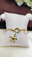 Gold bracelet with turtle charm, mother of pearl flower and pearl accent, displayed on cushion – stylish handmade jewelry for women