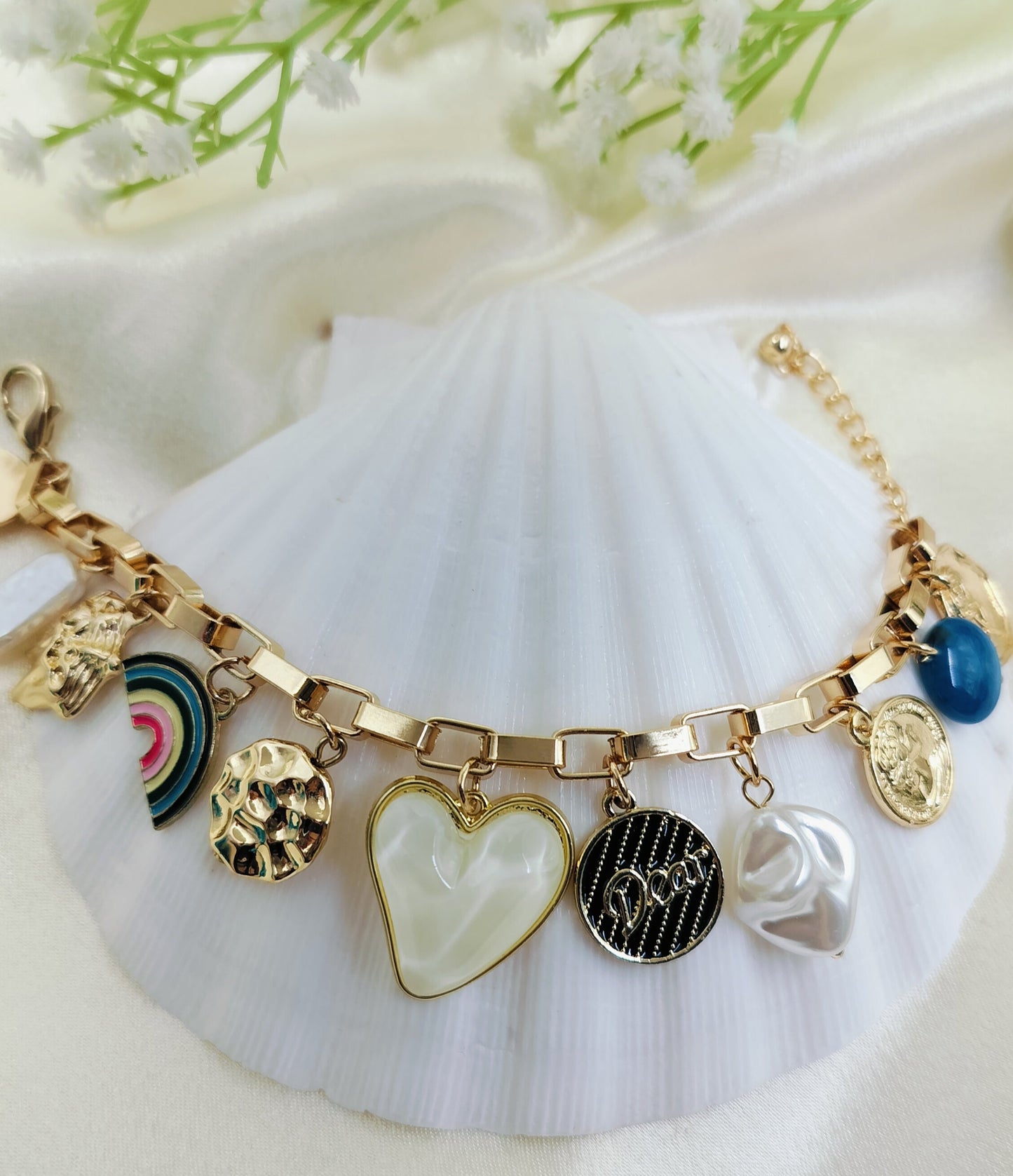 A gold charms bracelet with a variety of symbols and elements, displayed on a white surface.