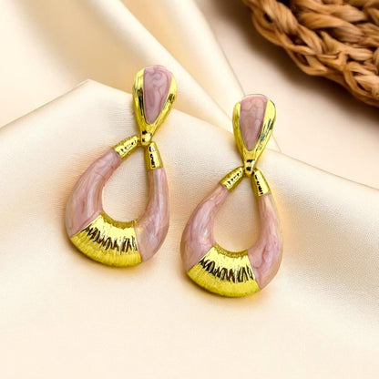 Pair of earrings with pink and gold design on a beige background