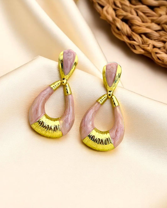 Pair of earrings with pink and gold design on a beige background