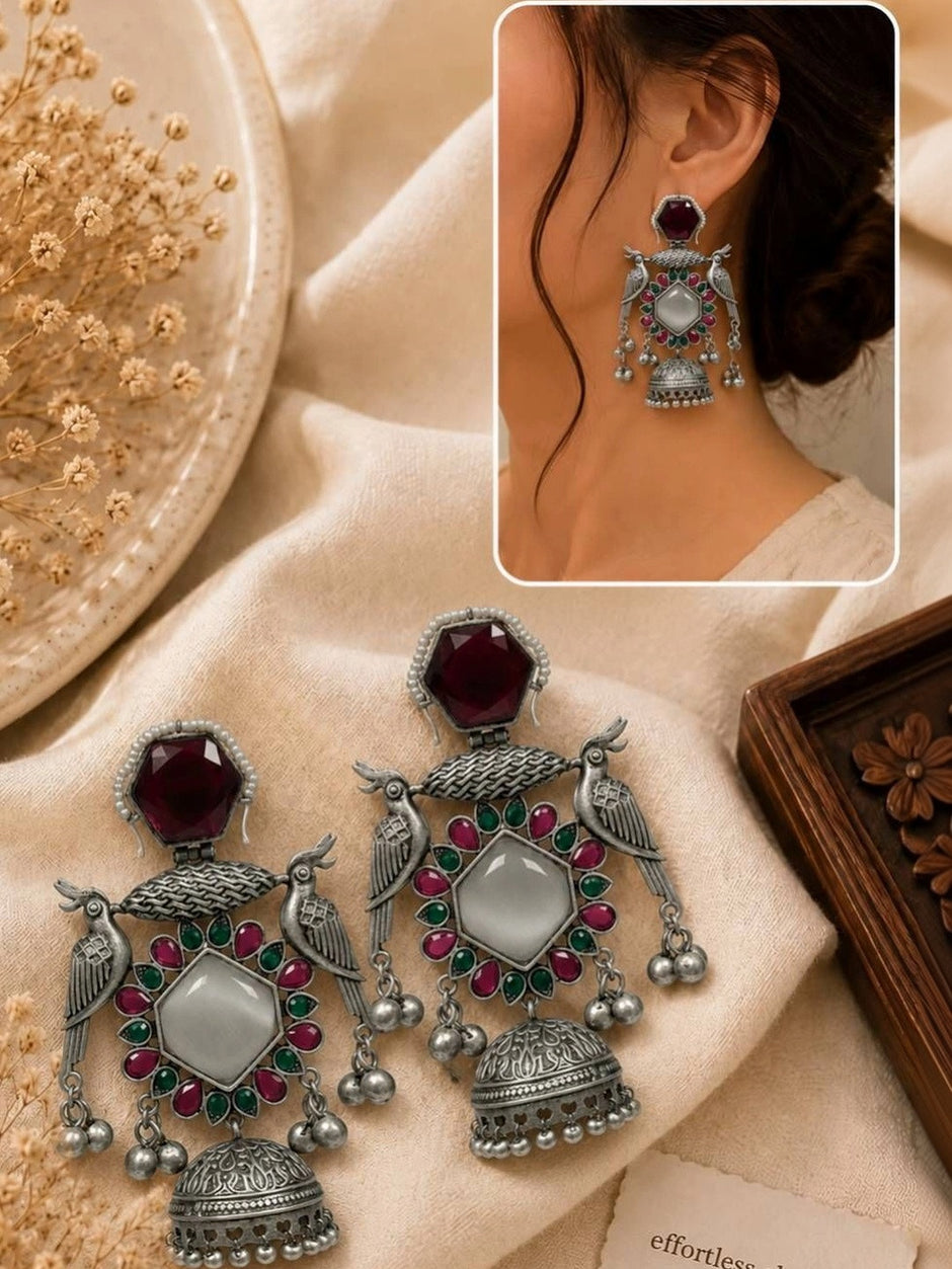 Peacock jhumka earrings displayed on ivory fabric with inset photo of earring worn on model's ear