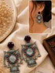 Peacock jhumka earrings displayed on ivory fabric with inset photo of earring worn on model's ear