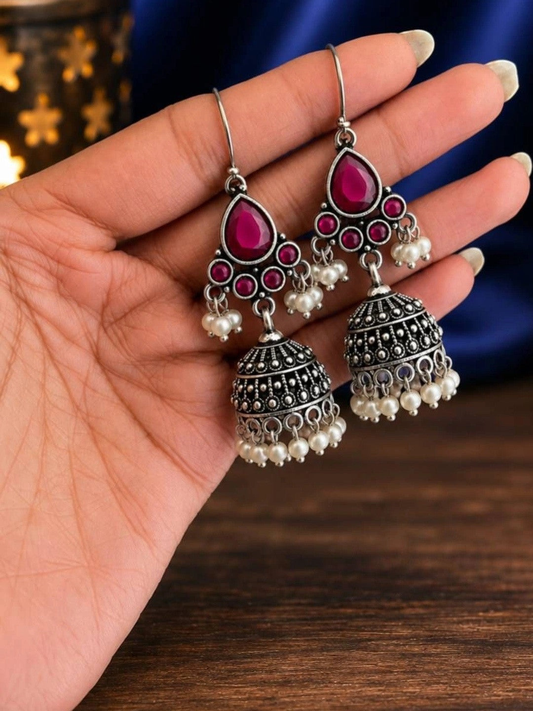 Two oxidised silver pearl drop jhumka earrings resting on an open palm showing scale and detail