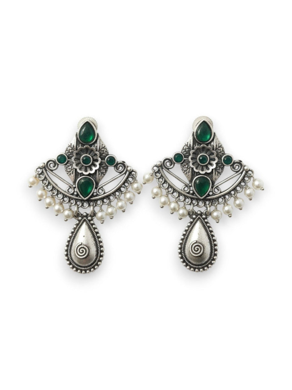 Pair of oxidised silver chandbali earrings with green stones and white pearl drops on white background