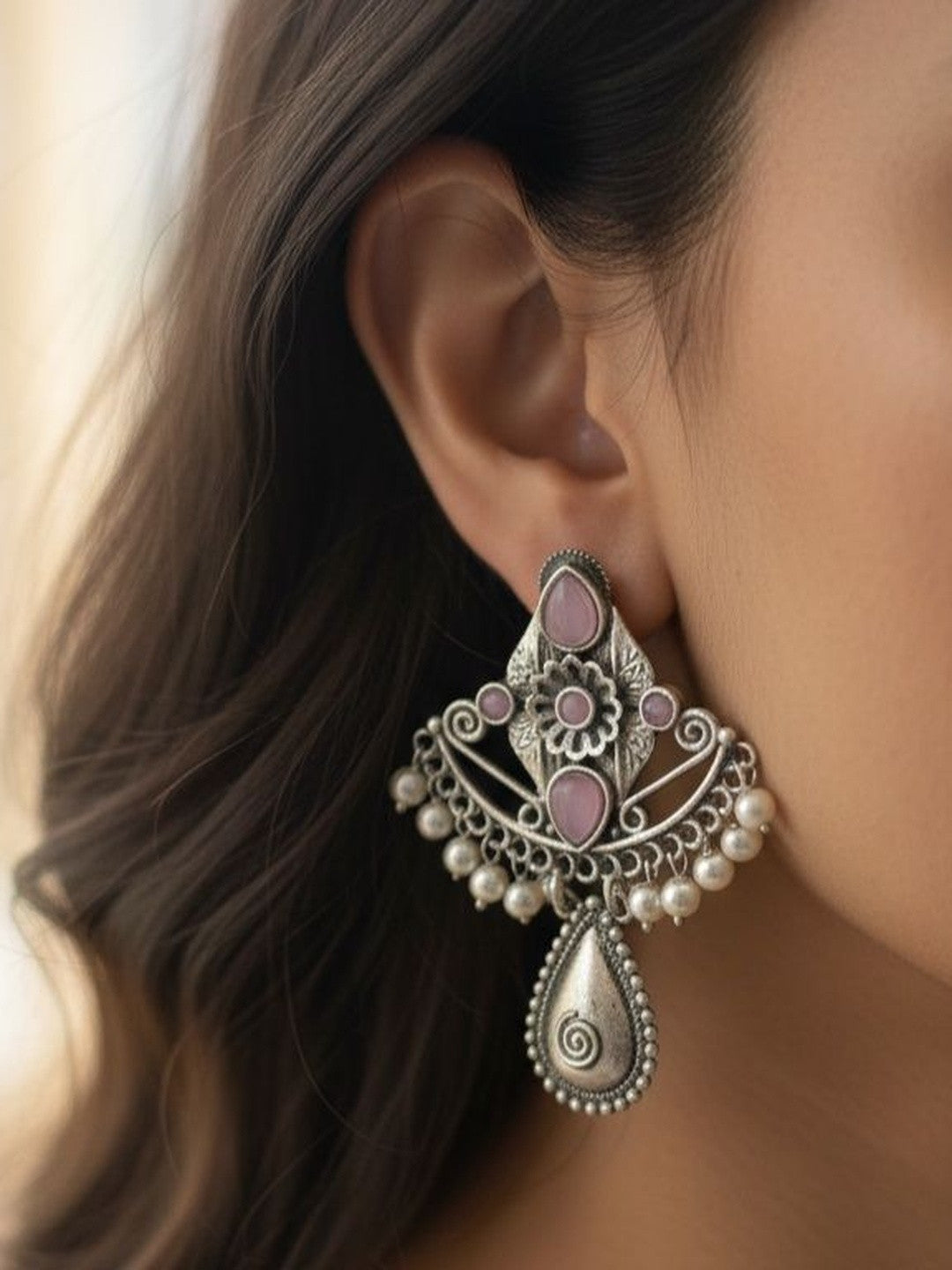 Model wearing one oxidised silver chandbali earring with pink stones and pearl fringe showing scale and fit on ear