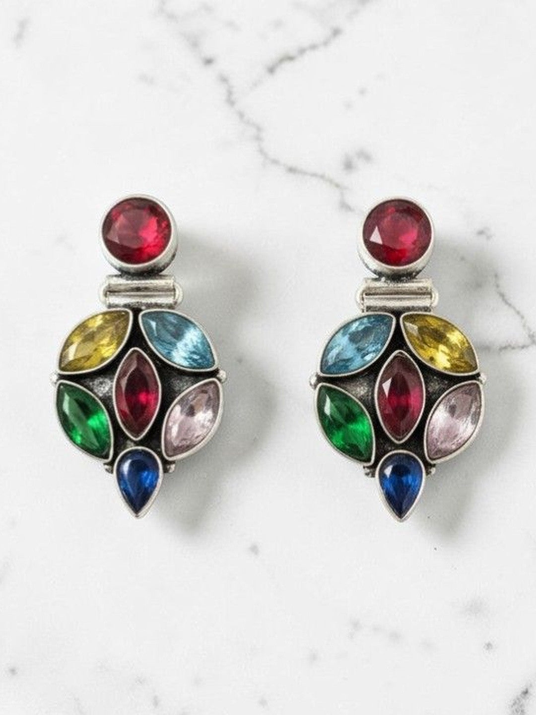 Pair of oxidised silver drop earrings with multicolour crystal stones on a white marble surface