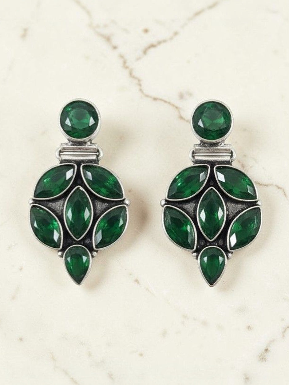 Pair of oxidised silver drop studs with emerald green marquise and round stones on marble surface