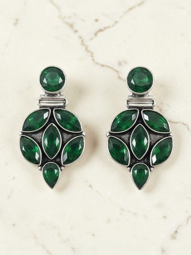 Pair of oxidised silver drop studs with emerald green marquise and round stones on marble surface