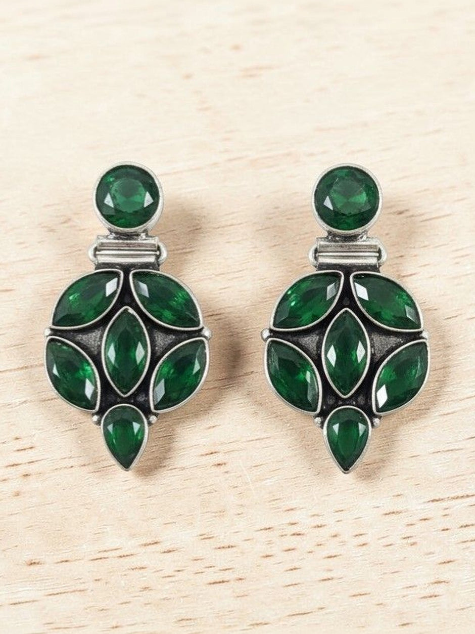 Front view of green stone oxidised silver cluster earrings displayed on a light wood background