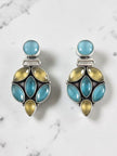 Pair of oxidised silver drop earrings with blue and yellow-green stone clusters on a marble background