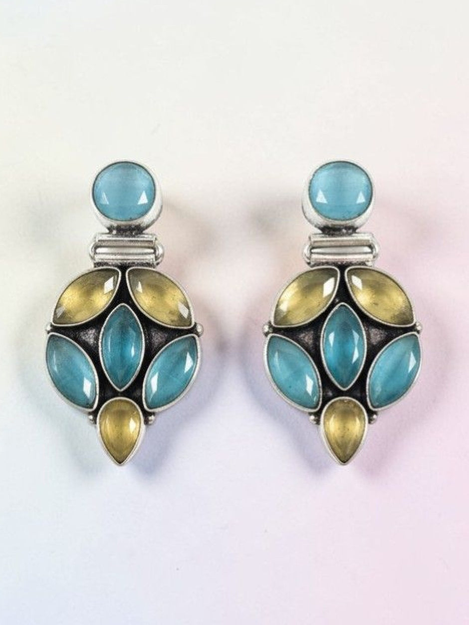 Front view of blue and yellow stone oxidised silver drop earrings on a light gradient background