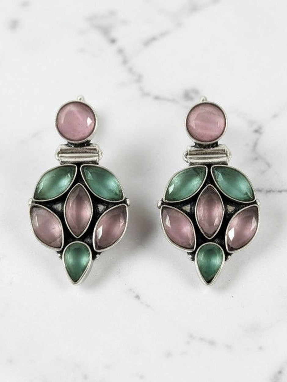 Close-up of oxidised silver floral cluster drop earrings with pink and green stones on white marble