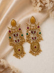 Pair of kundan drop earrings laid flat on ivory satin fabric with dried floral backdrop