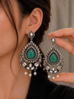 Model wearing oxidised silver green stone chandbali earring with second earring held up in hand