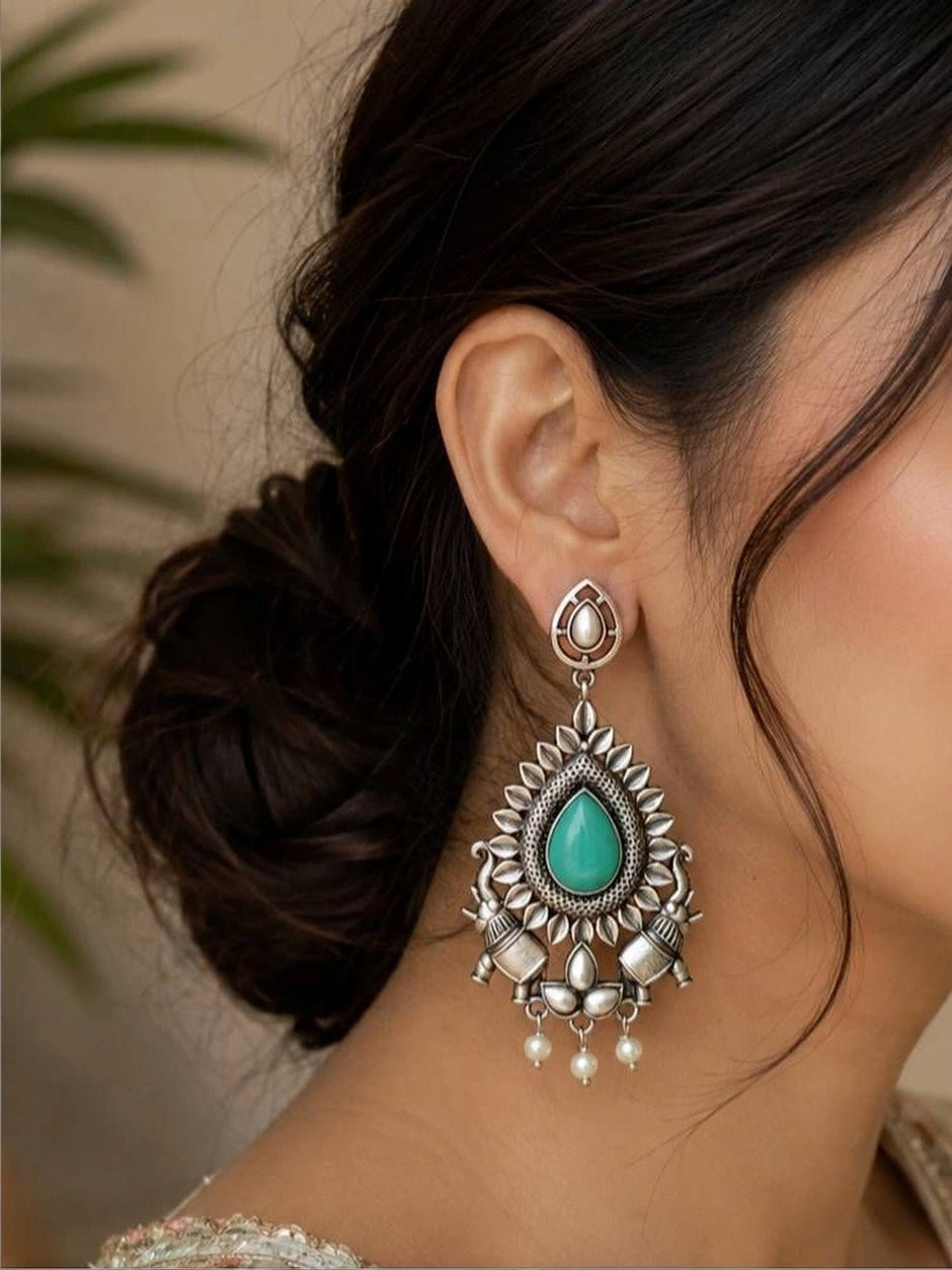 Close-up side view of oxidised silver teardrop chandbali earring worn on model with upswept hair