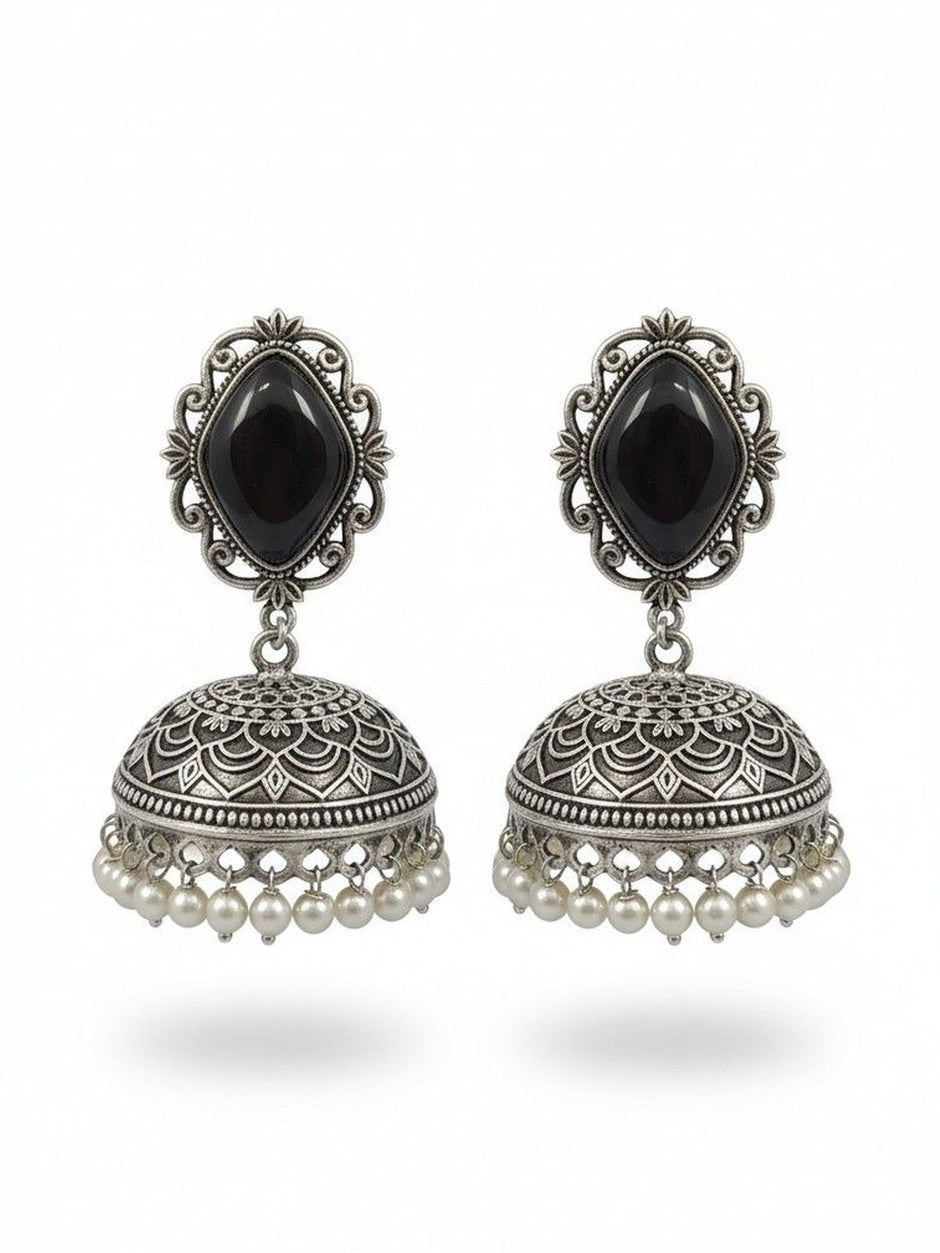 Pair of oxidised silver jhumka earrings with black stone tops and ivory pearl drops on white background