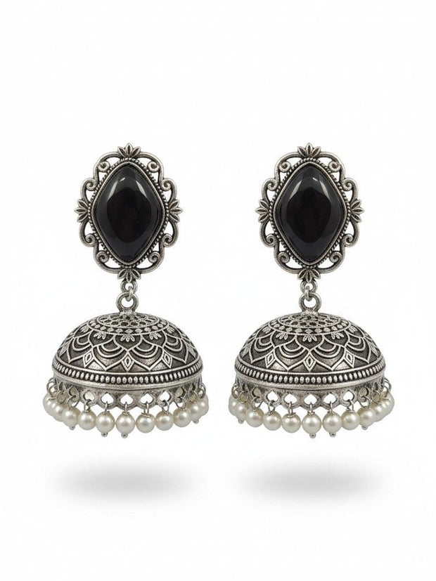 Pair of oxidised silver jhumka earrings with black stone tops and ivory pearl drops on white background
