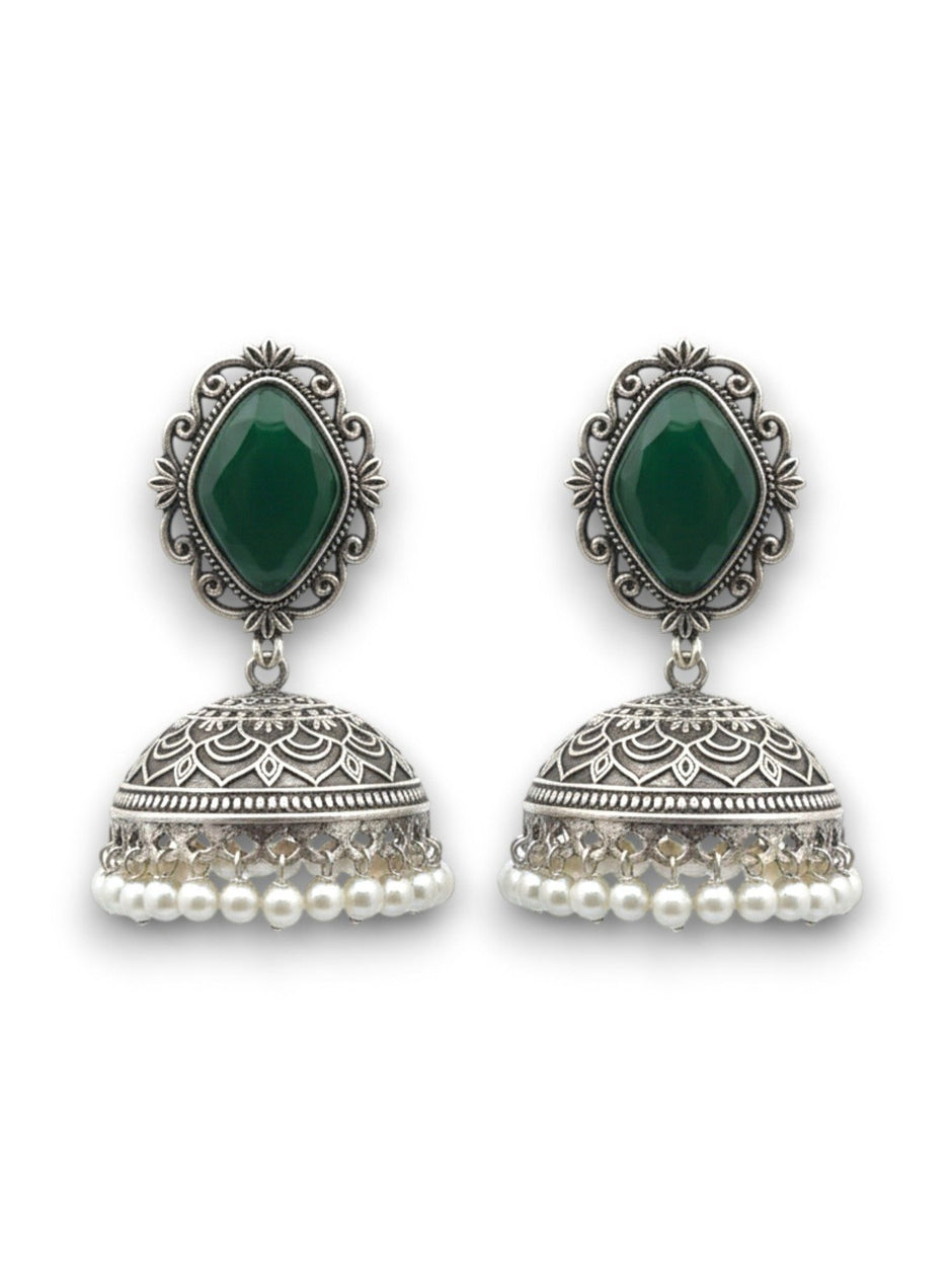 Pair of oxidised silver green stone jhumka earrings with engraved dome and pearl drops on a white background