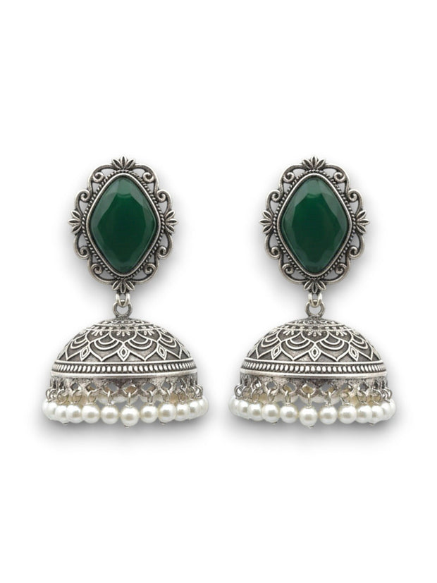 Pair of oxidised silver green stone jhumka earrings with engraved dome and pearl drops on a white background