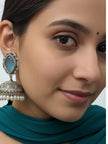 Close-up of oxidised silver jhumka earring worn on a woman's ear, shown with a teal outfit and a small bindi