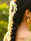 Gold-plated kundan chandbali earring worn by a woman with jasmine-adorned braid and gold saree blouse