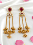 Pair of gold-plated kundan tassel earrings with ruby-red stone, pearl border, and clustered ghungroo drops on white satin