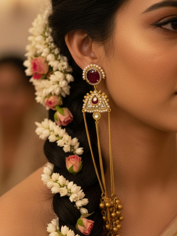 Close-up of kundan tassel earring worn on a bride's ear with jasmine and rose flower braid