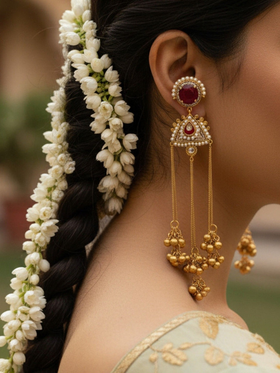 Side profile of model wearing gold kundan tassel earring with white jasmine floral braid and mint green embroidered blouse