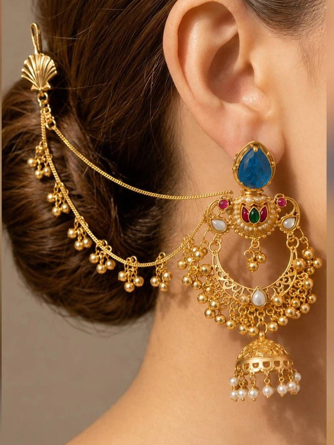 Gold-plated chandbali jhumka earring with hair chain worn on a woman with a low bun hairstyle, showing full drape and styling