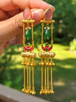 Both tassel jhumka earrings held in hand showing pink stone, green bead, meenakari crescent and ghungroo tassels
