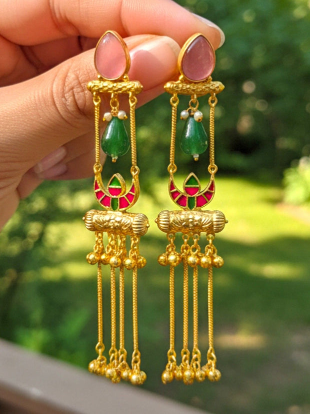 Both tassel jhumka earrings held in hand showing pink stone, green bead, meenakari crescent and ghungroo tassels