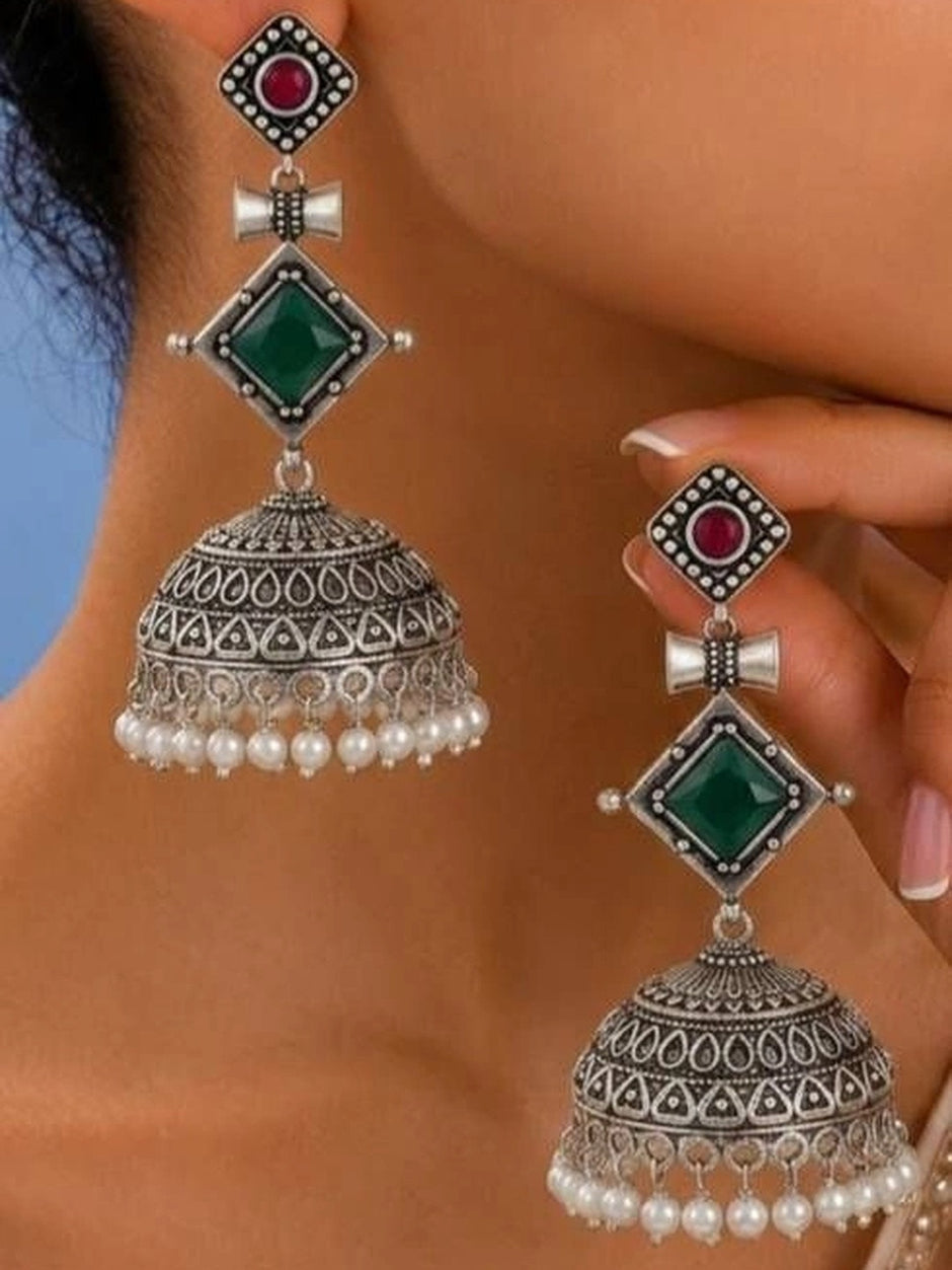 Oxidised silver jhumka earrings with green diamond stone and pearl drops worn on a woman's ear