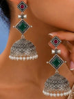 Oxidised silver jhumka earrings with green diamond stone and pearl drops worn on a woman's ear