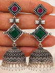 Close-up of oxidised silver jhumka earring pair held on a hand showing engraved dome and pearl fringe detail