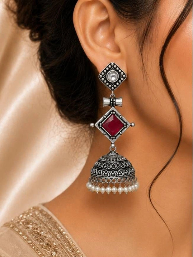 Oxidised silver geometric jhumka earring worn on a woman's ear with pearl fringe dangling below