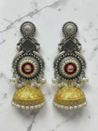 Pair of oxidised dual-tone kundan jhumka earrings with pearl drops on a white marble surface