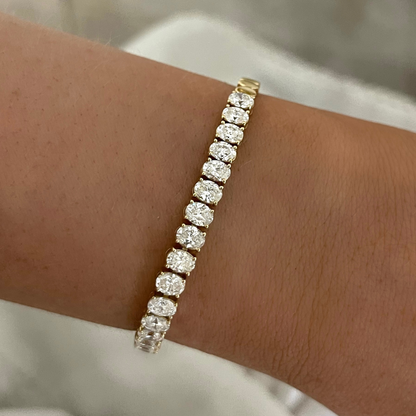Gold tennis bracelet with sparkling round stones worn on the wrist.