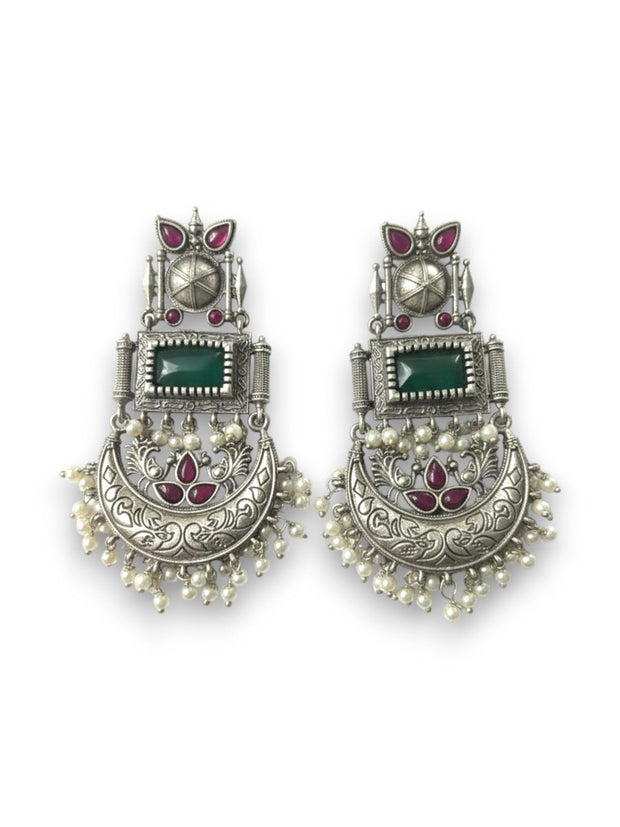 Two oxidised silver chandbali earrings laid flat showing engraved crescent moon and pearl drop detail