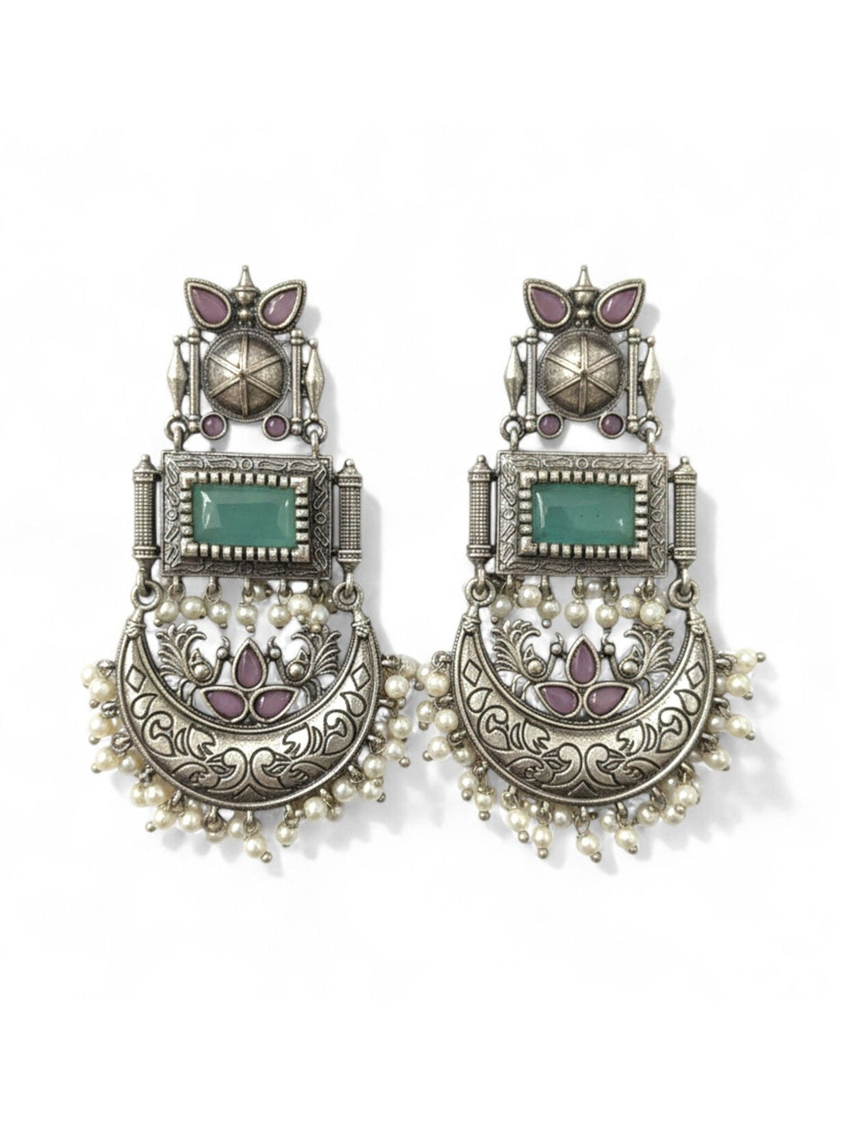 Pair of oxidised silver chandbali earrings with green stone, mauve accents and pearl drops on white background