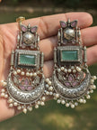 Both oxidised silver chandbali earrings held in a woman's palm showing engraved lotus and pearl drop details