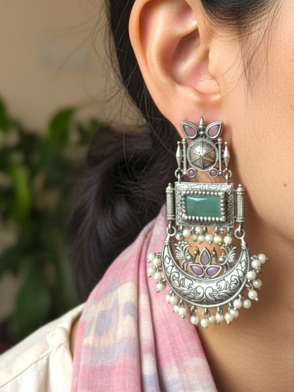 Single oxidised silver chandbali earring worn on ear alongside a pink ikat dupatta showing full length and scale