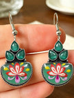 Close-up of both meenakari hook earrings resting on a hand, showing vivid red, pink and yellow lotus enamel detail